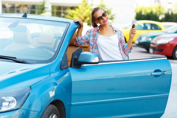 Woman in sunglasses standing near convertible with keys in hand — Stock fotografie