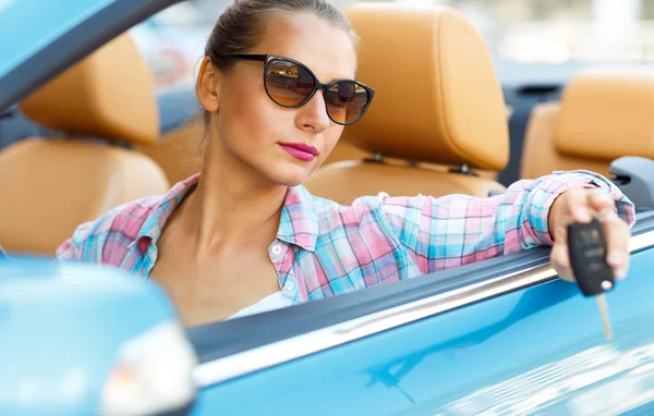 Woman in sunglasses sitting in a convertible car with the keys i Stock Picture