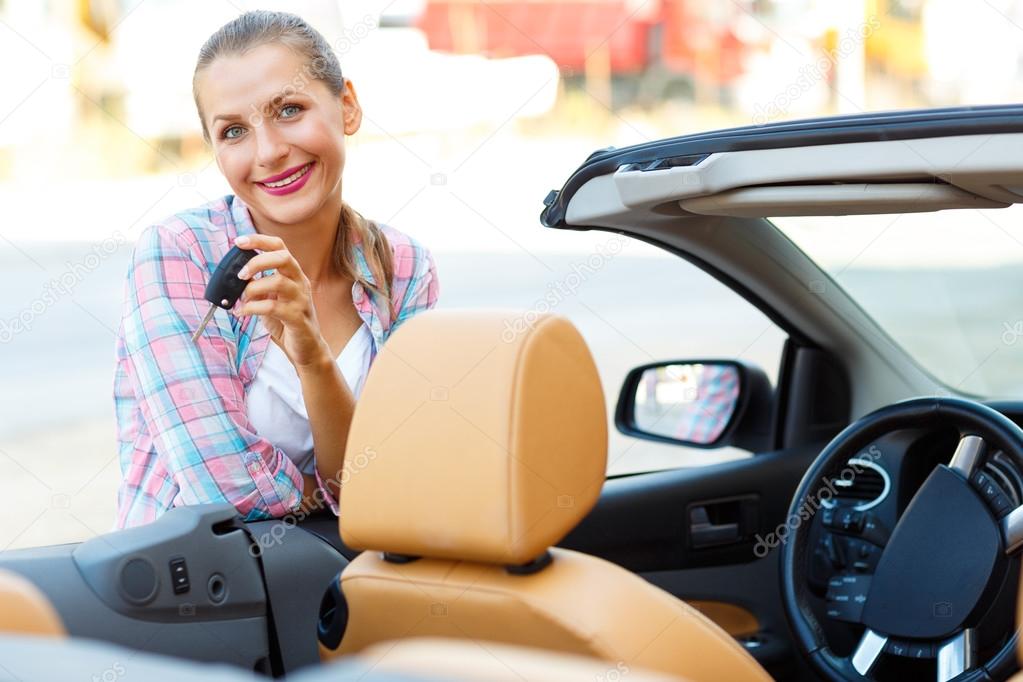Woman standing near a convertible with keys in hand - concept of