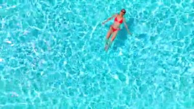 Pembe mayo giymiş bir kadının havuzda sırt üstü yüzüşü. Rahatlatıcı konsept, yaz yaşam tarzı. Yavaş çekim