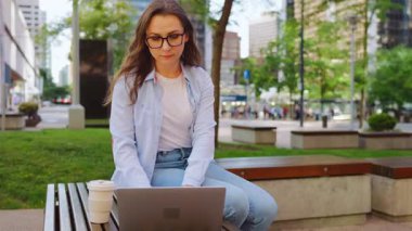 Parkta dizüstü bilgisayarıyla oturan ve yaz boyunca çalışan bir kadın. Yörünge atışı