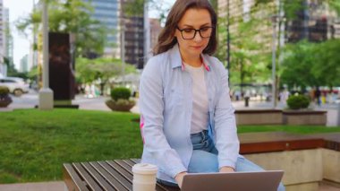 Parkta dizüstü bilgisayarıyla oturan ve yaz boyunca çalışan bir kadın. Yörünge atışı