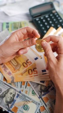 Erkek eli, BTC bitcoin 'i farklı para birimlerinin banknotları olan dolar ve avrolar ile karşılaştırır ve döndürür. Kripto para birimi kavramı ve engelleme teknolojisinin geniş dünyası..