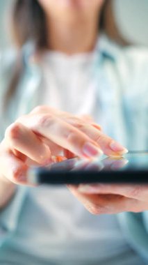 Kurye uygulaması kullanarak akıllı telefondan sosyal medya kaynaklarını tarayan bir kadın. Elinde cep telefonu olan bir kadın. Dikey