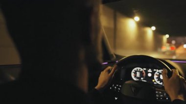 Akşam şehrinin sokaklarında araba süren bir adamın arka koltuğu. Araba ışıkları ve trafik ışıkları her yerde..