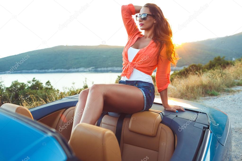 Beautiful woman sitting in cabriolet, enjoying trip on luxury mo