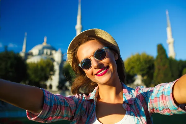 Menina no chapéu fazendo selfie pelo smartphone no backgroun — Fotografia de Stock