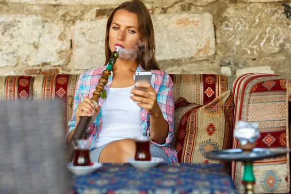 Mulher fumando um narguilé e usa smartphone em um café em Istambul — Fotografia de Stock