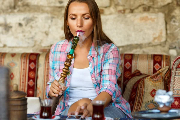 Woman smoking a hookah and uses smartphone in a cafe in Istanbul — Stockfoto