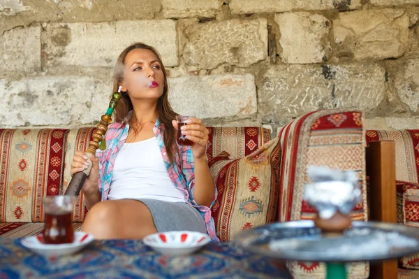 Woman smoking a hookah and drinking tea in a cafe, Istanbul, Tur