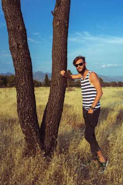 Jonge stijlvolle knappe man in de savanne — Stockfoto