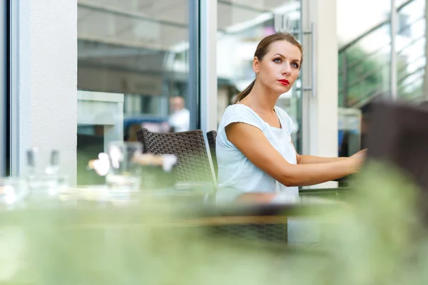 Young woman with red lips reads a newspaper sitting in a cafe — Stock Photo, Image