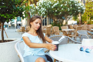 Kahve içme ve kafede gazete okuyan genç kadın