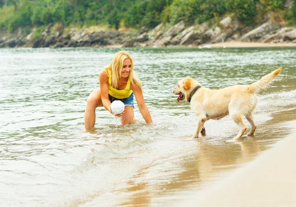 Mujer con perro jugando en la playa —  Fotos de Stock