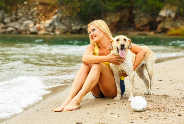 Mulher com cão brincando na praia — Fotografia de Stock