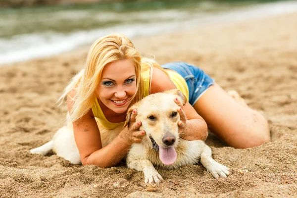 Frau mit Hund spielt am Strand — Stockfoto