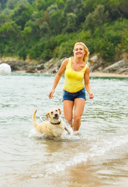 Woman with dog playing on the beach — Stock Photo, Image