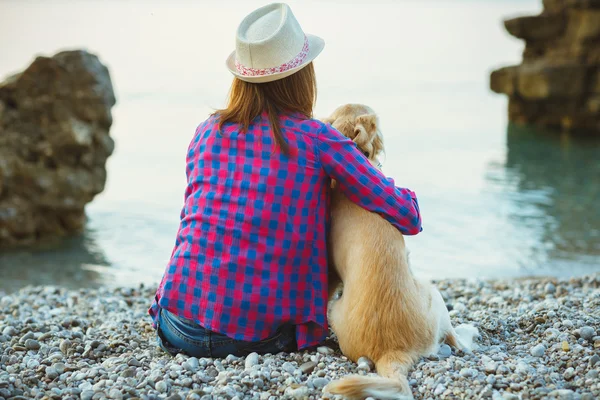 Woman with a dog sitting on the beach — Stock Photo, Image