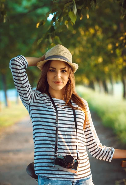 Preciosa joven en un sombrero montando una bicicleta en un parque — Foto de Stock