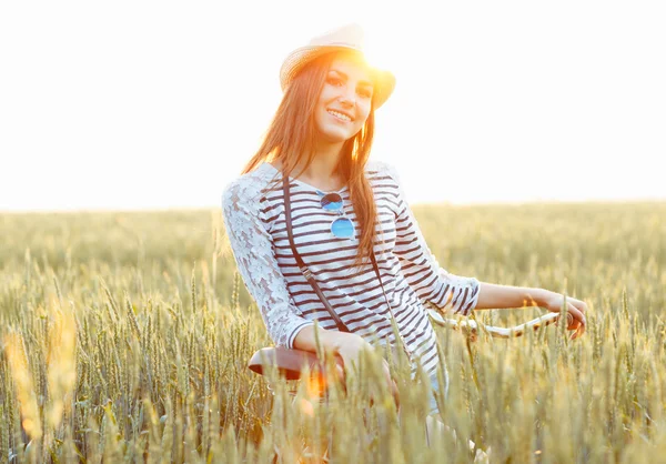 Lovely young woman stands in a field with her bicycle — Stock Photo, Image