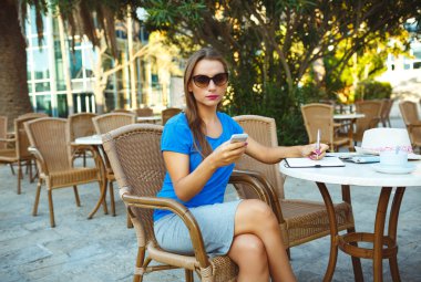 Young pretty modern blogger using smartphone and makes notes in 