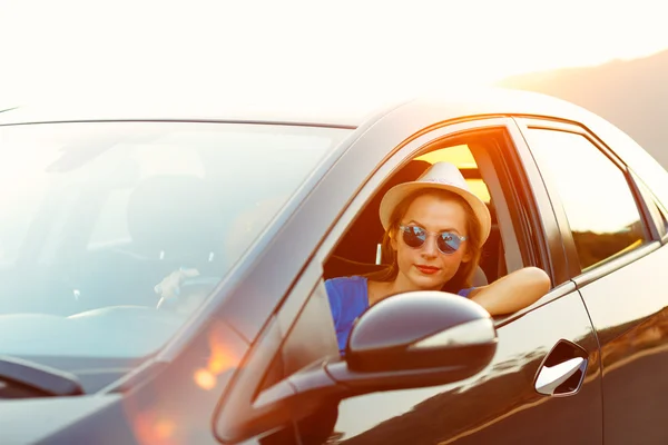 Donna sorridente alla guida di una macchina al tramonto — Foto Stock