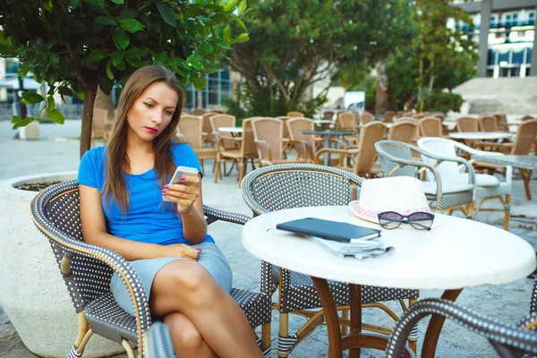 Jovem mulher bonita relaxando no café ao ar livre e usando smartp — Fotografia de Stock