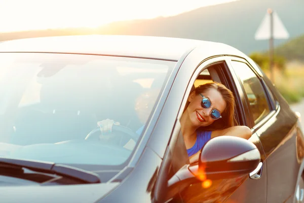 微笑的女士在日落时驾驶一辆车 — 图库照片