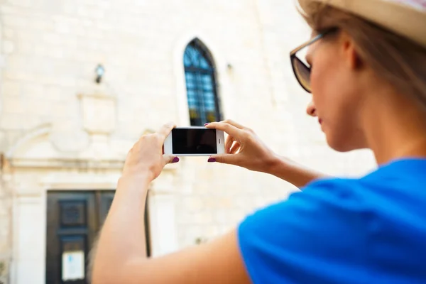 Lány kalapban képeket egy templom azáltal, hogy a smartphone — Stock Fotó