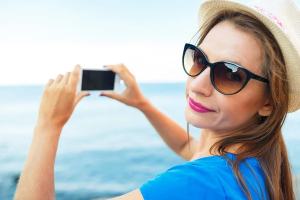 Chica en sombrero haciendo fotos del mar Adriático por el teléfono inteligente — Foto de Stock