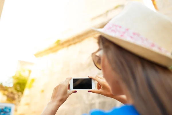 Lány kalapban képeket egy templom azáltal, hogy a smartphone — Stock Fotó