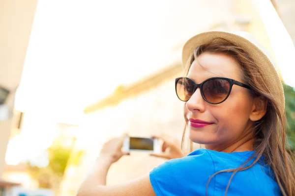 Chica en sombrero haciendo fotos de una iglesia por el teléfono inteligente — Foto de Stock