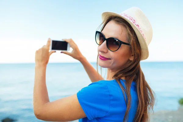 Menina de chapéu fazendo fotos do mar Adriático pelo smartphone — Fotografia de Stock