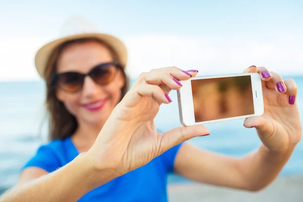 Menina no chapéu fazendo selfie pelo smartphone no backgroun — Fotografia de Stock