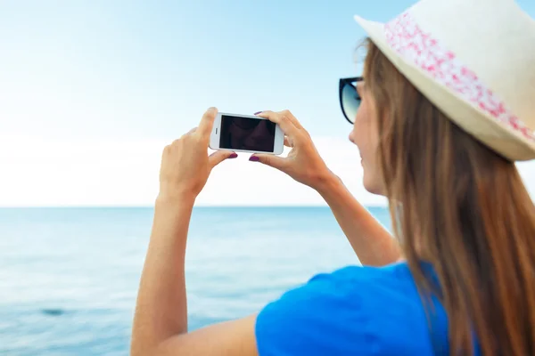 Menina de chapéu fazendo fotos do mar Adriático pelo smartphone — Fotografia de Stock