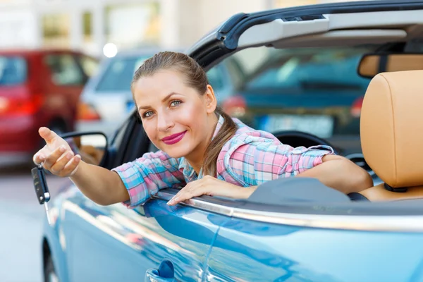 Joven mujer bonita sentada en un coche descapotable con las llaves en — Foto de Stock