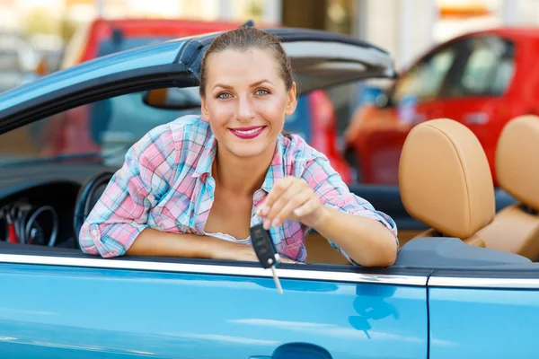 Joven mujer bonita sentada en un coche descapotable con las llaves en — Foto de Stock