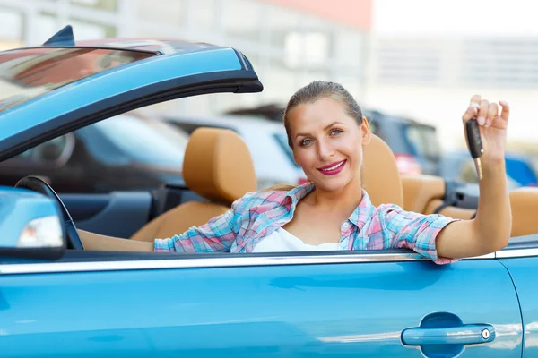 Jovem mulher bonita sentada em um carro conversível com as chaves em — Fotografia de Stock