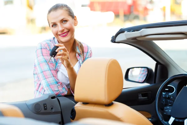 Junge Frau steht neben einem Cabrio mit Schlüssel in der Hand — Stockfoto