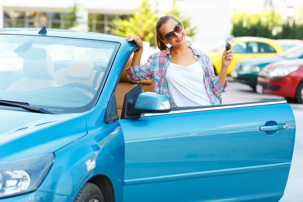 Mujer bonita joven en gafas de sol de pie cerca convertible con — Foto de Stock