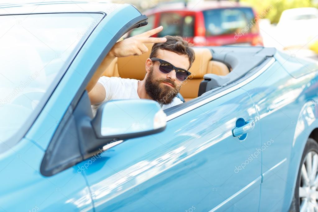 A young bearded man sitting in a convertible