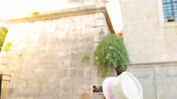 Chica en sombrero haciendo fotos de una iglesia por el teléfono inteligente — Vídeos de Stock