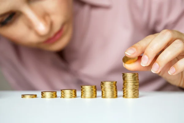 Mujer de negocios apilando monedas de oro en columnas crecientes — Foto de Stock