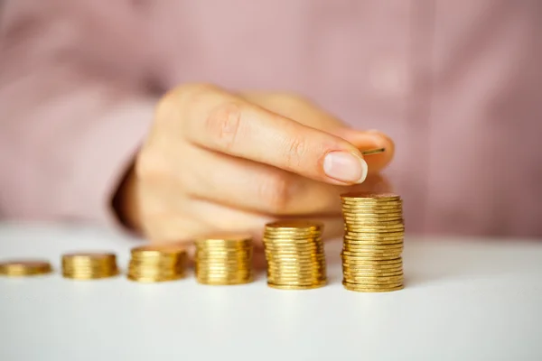 Weibliche Hand stapelt Goldmünzen in zunehmenden Säulen — Stockfoto