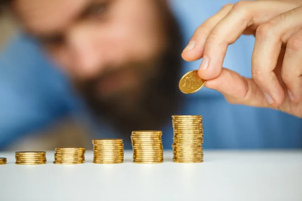 Hombre de negocios apilando monedas de oro en columnas crecientes —  Fotos de Stock