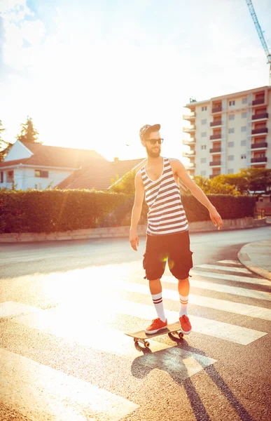 Man in sunglasses with a skateboard on a street in the city at s