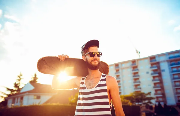 Man in zonnebril met een skateboard op een straat in de stad op s — Stockfoto