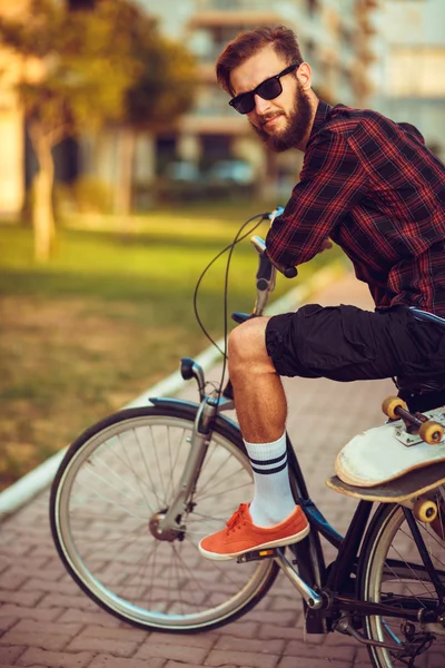 Man in sunglasses riding a bike on city street — Stock Photo, Image