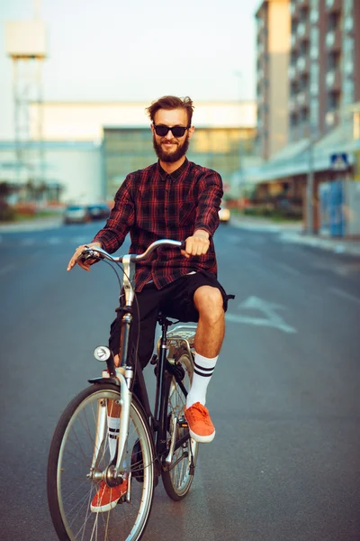 Man in sunglasses riding a bike on city street — Stock Photo, Image