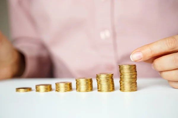 Mano femenina apilando monedas de oro en columnas crecientes — Foto de Stock